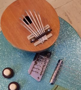 A kalimba sitting on top of a sparkly turquoise electric guitar